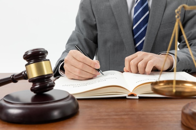 Closeup shot of a person writing in a book with a gavel on the table